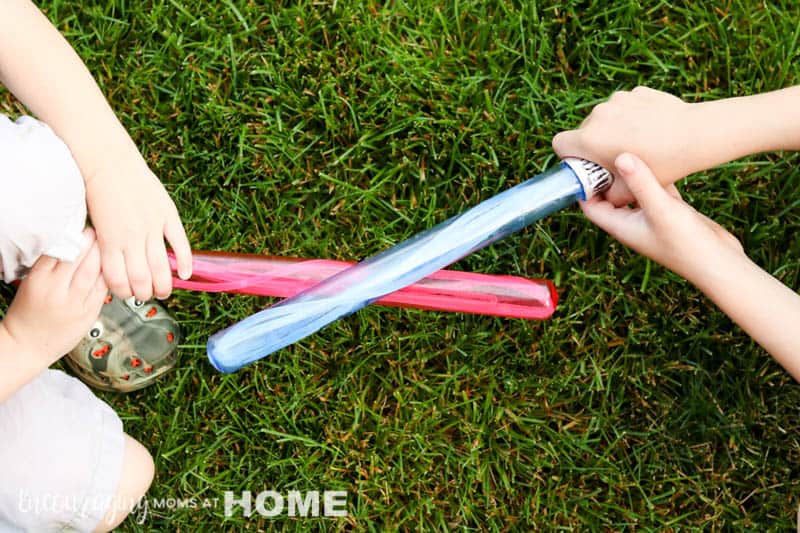 Two kids facing off with bubble wand Star Wars light sabers