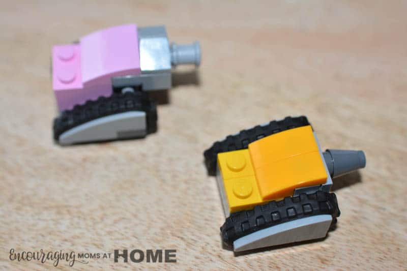 Pink and Yellow mini Lego tanks face an imaginary opponent.